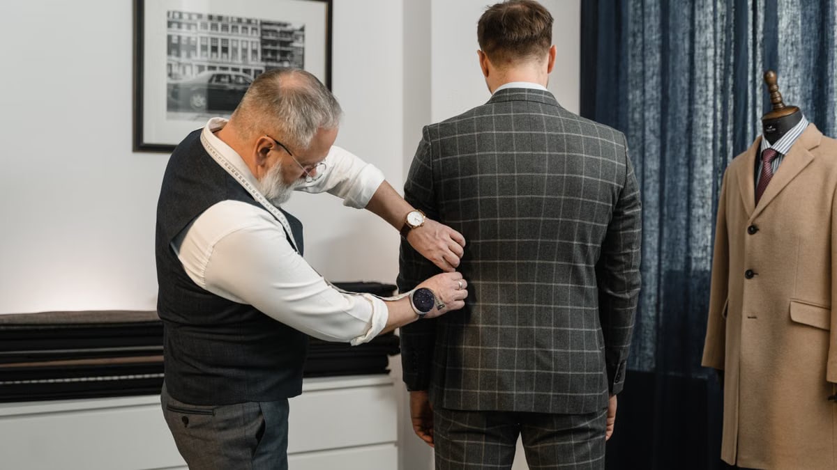 Tailor making precise adjustments to a custom suit in a professional atelier setting.